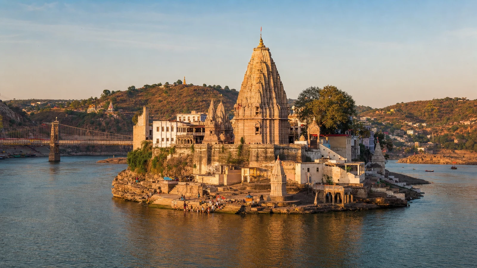 Omkareshwar Jyotirlinga Temple on Mandhata island in the Narmada River, Madhya Pradesh, with ghats, hills and a bridge.